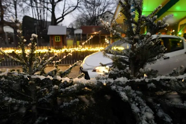 A car drives through artificial snow at a Christmas market