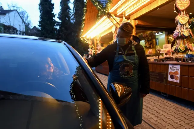 A woman buys food from a booth at a Christmas market