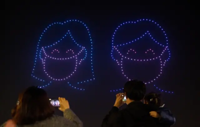 Drones form the shape of two people wearing masks