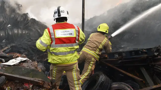 Firefighters work to put out the fire among burning tyres