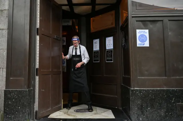 worker wears a shielding face mask as he prepares to close the pub