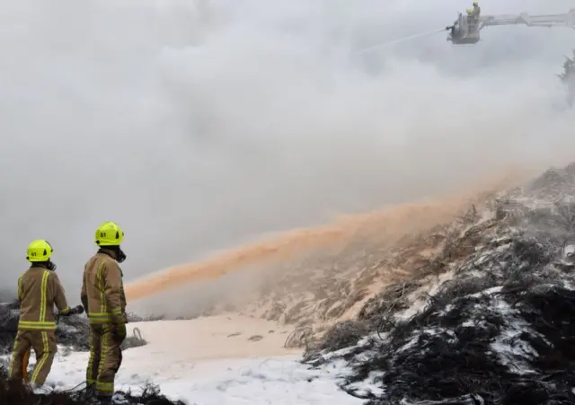 Firefighters pumping their foam onto tyres