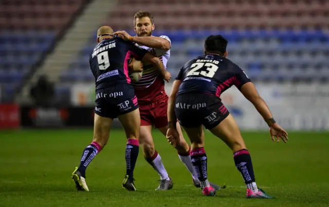 Sean O'Loughlin of Wigan is tackled by Danny Houghton and Andre Savelio of Hull FC