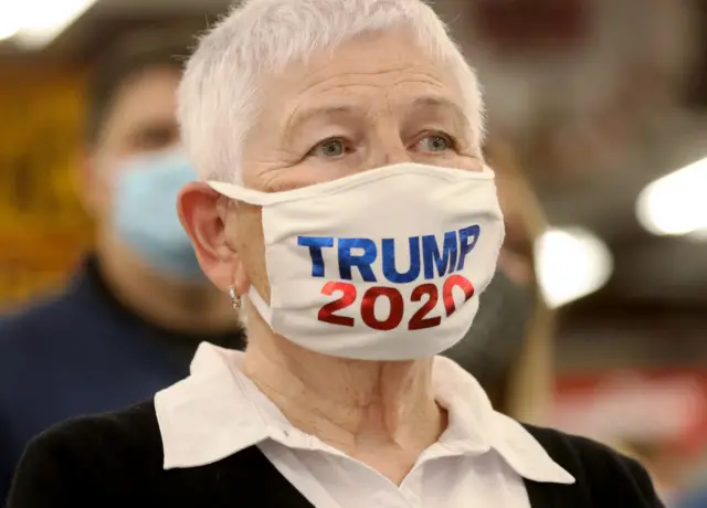 A woman wears a 'Trump 2020' face mask