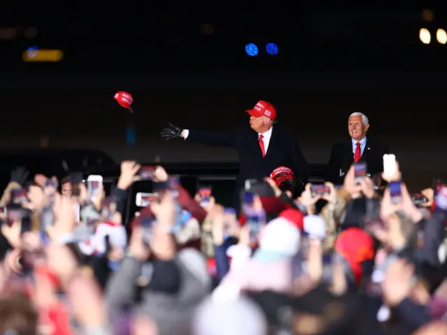 President Donald Trump throws hats to supporters with Vice-President Mike Pence during a rally on November 2, 2020