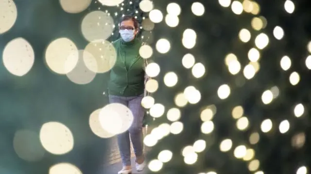 Woman walks past Christmas lights