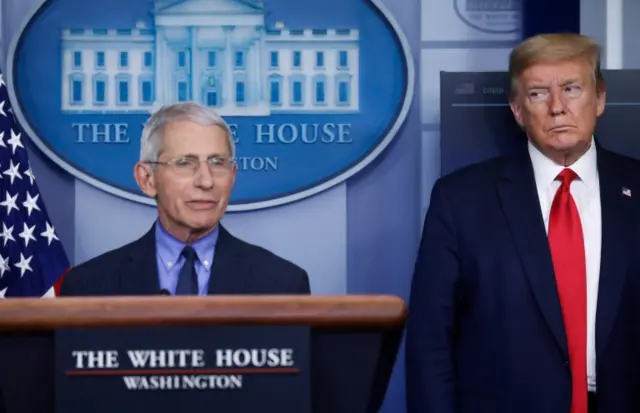 President Donald Trump (R) looks at Dr Anthony Fauci during a briefing