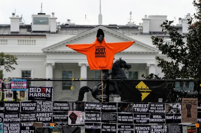 Anti-Trump signs line a White House security fence ahead of election day