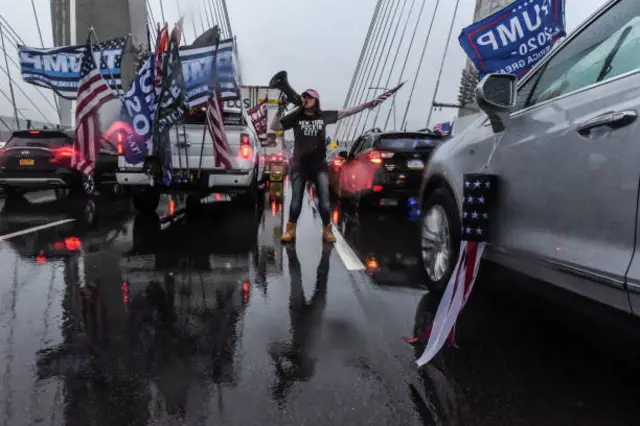 A trump supporter with a megaphone stands in the middle of a NYC bridge