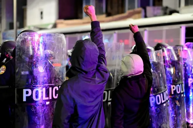 Demonstrators raise their fists in front of police officers during a rally after the death of Walter Wallace Jr., a Black man who was shot by police in Philadelphia, Pennsylvania