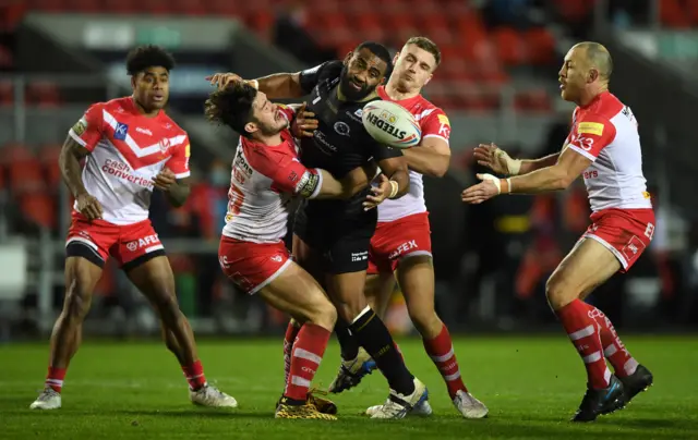 Samisoni Langi of Catalans loses the ball under pressure from Lachlan Coote of St Helens