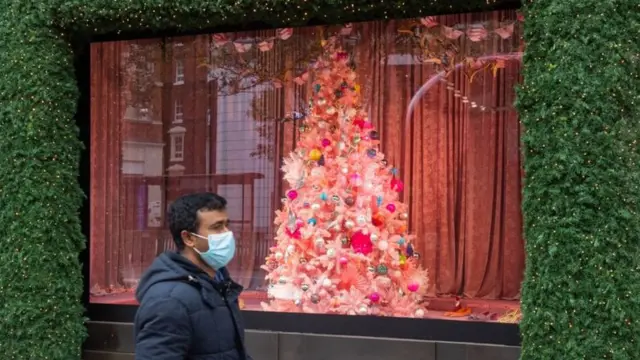 Man in a mask in front of a Christmas tree