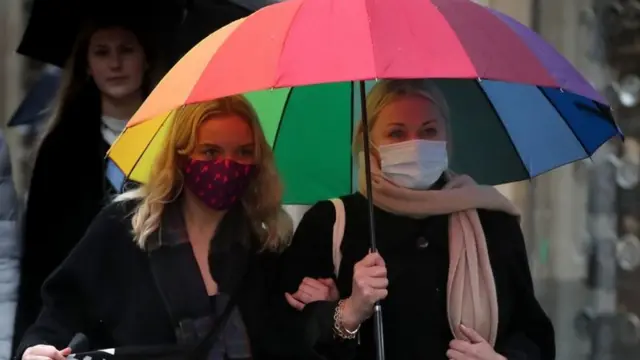 Women in masks under umbrellas