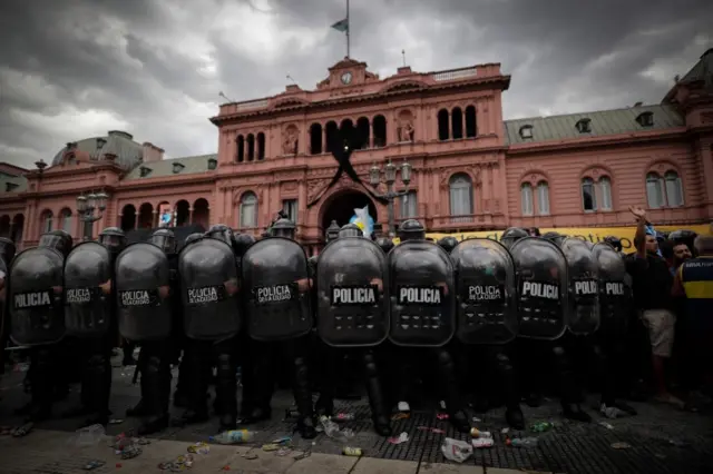 Riot police on guard as fans of soccer legend Diego Armando Maradona confront them as people wait to visit Maradona"s funeral chapel installed at the Casa Rosada in Buenos Aires, Argentina, 26 November 2020.