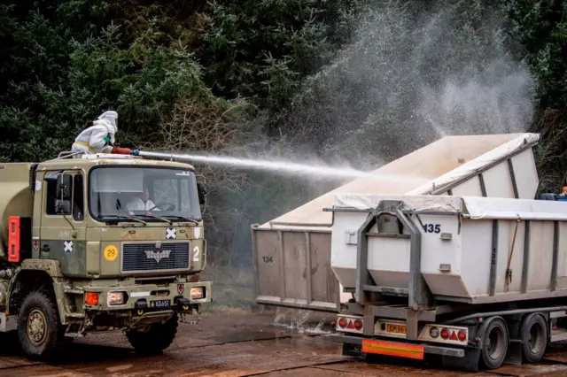 Men in hazmat suits desinfect truck containers the Danish health authorities dispose of dead mink in a military area near Holstebro, Denmark, 9 November 2020