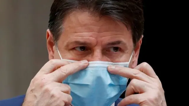 Italian Prime Minister Giuseppe Conte adjusts a protective face mask