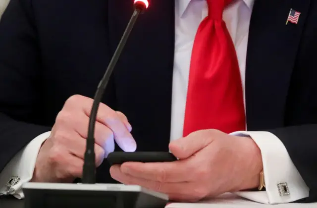 President Donald Trump taps the screen on a mobile phone