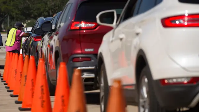 An election worker accepts ballots from voters in cars at a drive-through mail ballot drop-off site at NRG Stadium on October 7, 2020 in Houston, Texas.