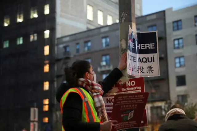 A worker tapes signs for voters before polls open, outside Brooklyn Public Library in New York, U.S., November 3, 2020. REUTERS/Caitlin Ochs