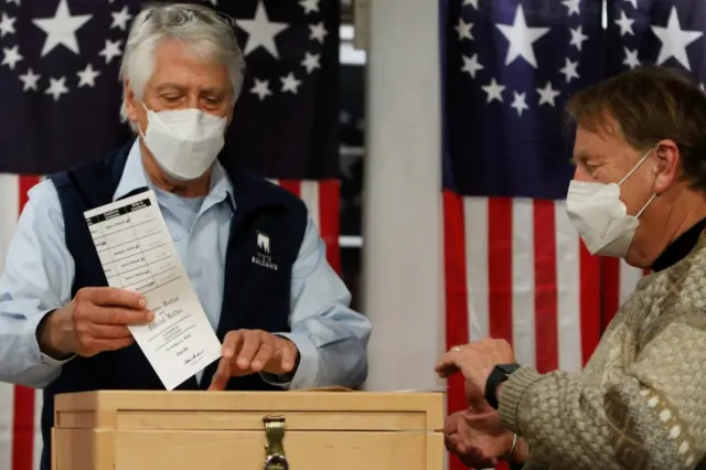 A man drops a ballot in a box shortly after midnight in the hamlet of Dixville Notch