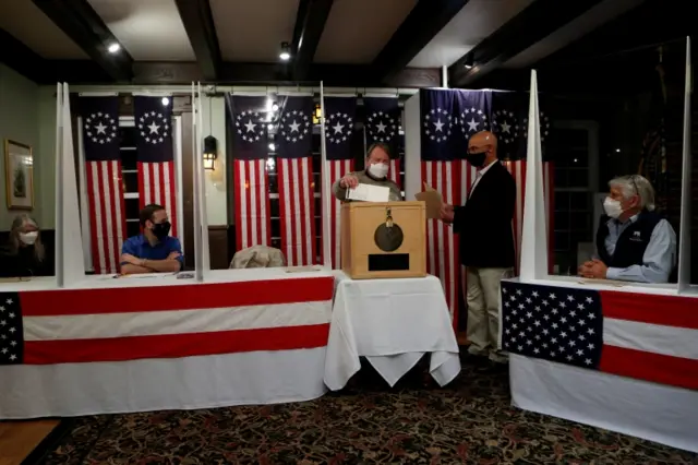 A man hands his ballot to town moderator Tom Tillotson to be put into a box for the presidential election at the Hale House at Balsams Hotel in the hamlet of Dixville Notch