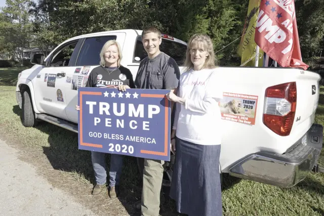 Amelia Crane (right) supports President Trump outside of a polling place with her 16-year-old son Samuel, and Angela Davison.