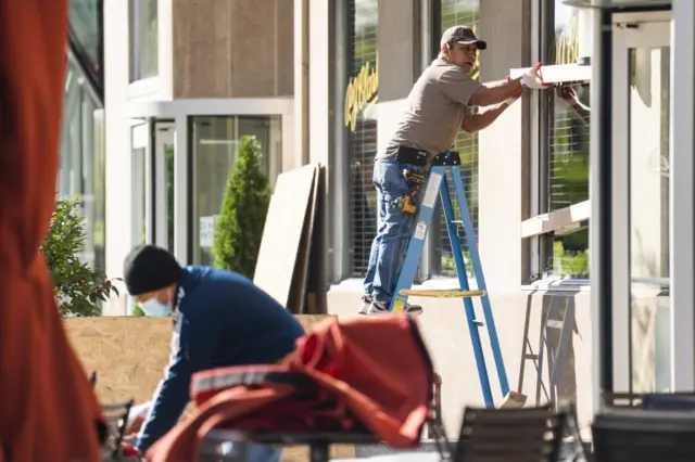 Workers board up the windows of a restaurant in Washington, DC