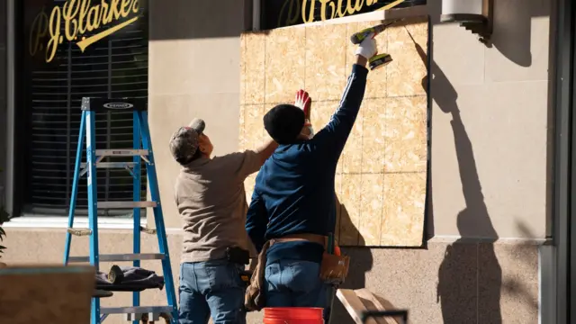 One day ahead of the US presidential election, workers board the windows of a restaurant inside Black Lives Matter (BLM) Plaza in Washington, DC, 02 November 2020.