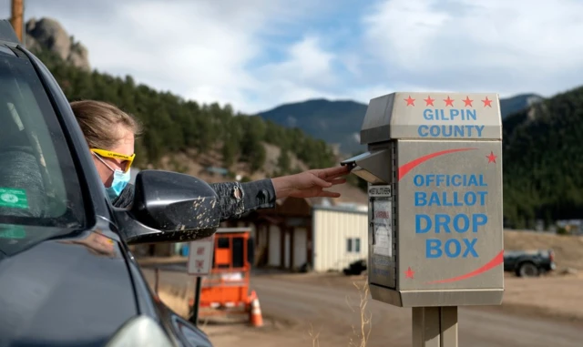 A voter drops off her ballot in Rollinsville, Colorado