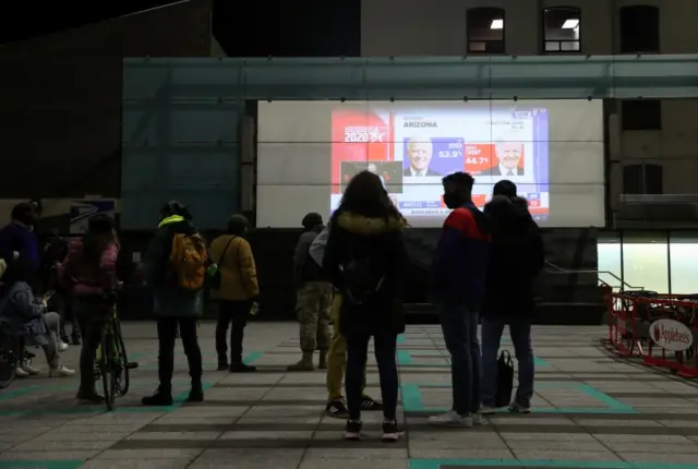 People watch early results come in from Arizona, outside during Election Day in downtown Brooklyn, New York