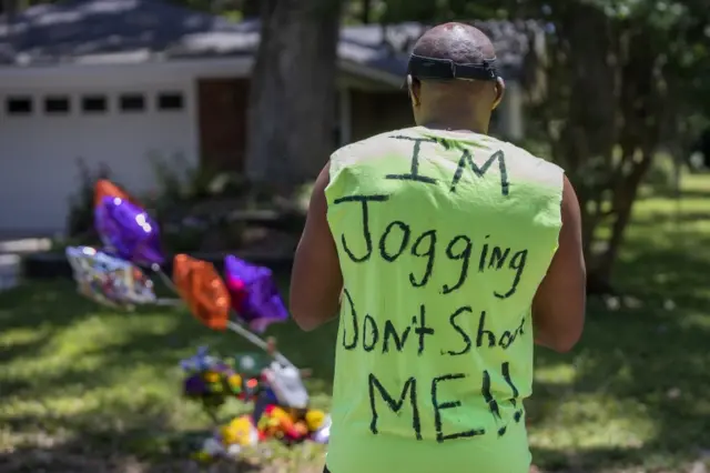 People gather at the small memorial at the site of the shooting death of unarmed black jogger Ahmaud Arbery in the Satilla Shores subdivision of Brunswick, Georgia, 8 May 2020