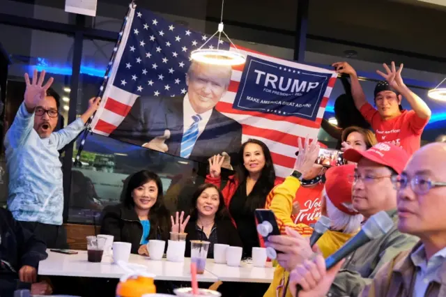 Voters gather round a Trump flag at an election watch party in Texas