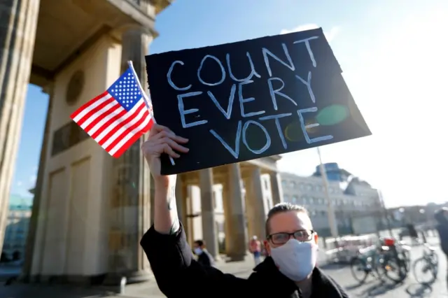 A demonstrator holds a placard and a US flag during a rally in Washington