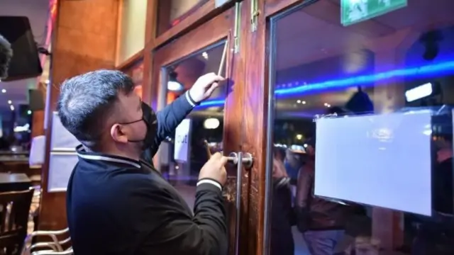 A man closing a bar as the regulations begin in England