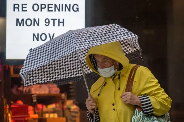 A woman wearing a face mask walks past a shop