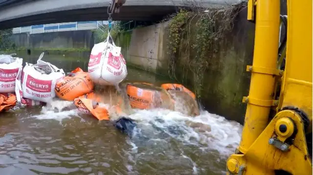 A makeshift dam being removed to allow the water to flow