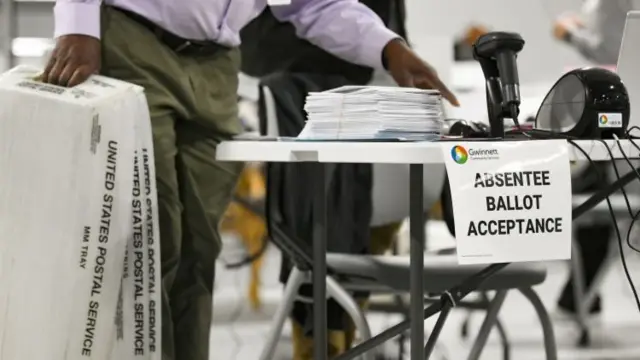 A poll worker looks over absentee mail in ballots after putting them on his desk at Gwinnett County Elections headquarters in Lawrenceville, Georgia, 3 November 2020