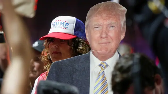 A supporter of US President Donald Trump carries a cardboard cutout of Trump during a protest about the early results of the 2020 U.S. presidential election, in Phoenix, Arizona,  November 6, 2020.