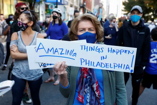 A woman holds a placard as media announce that Democratic US presidential nominee Joe Biden has won the 2020 U.S. presidential election, in, Philadelphia, Pennsylvania, U.S., November 7, 2020.