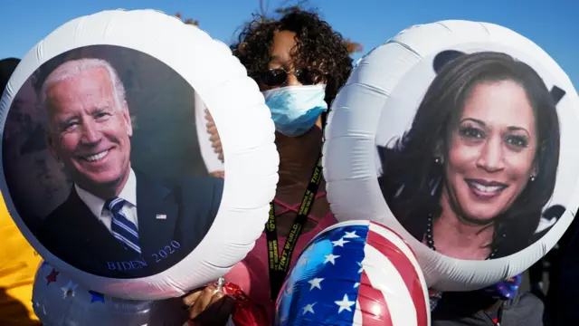 A Biden supporter holds balloons with the faces of Joe Biden and Kamala Harris as she celebrates in Wilmington, Delaware, 7 November, 2020