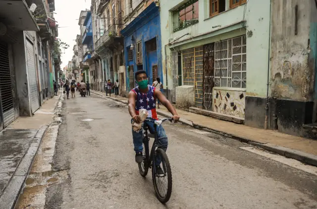 A man wearing a top with a design of the US flag rides on his bicycle along a street of Havana, on November 3, 2020