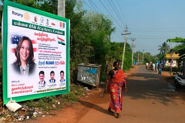 A woman walks past a poster of US Democratic vice-presidential candidate, Kamala Harris, at her ancestral village of Thulasendrapuram in the southern Indian state of Tamil Nadu on November 3, 2020