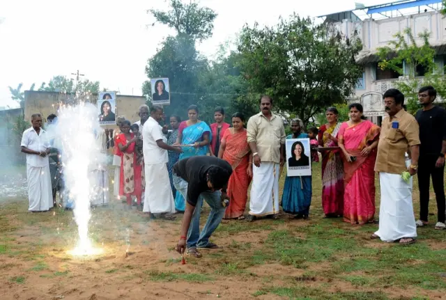 A man lights fireworks as villagers gather to celebrate