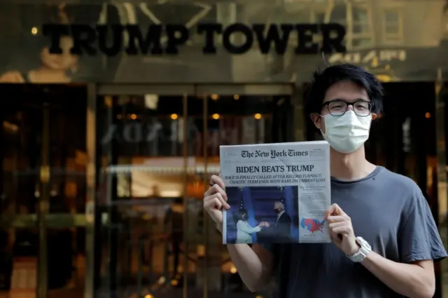 Bo Lim of Philadelphia - a city that was crucial to Biden's win - posed with a copy of the New York Times outside Trump Tower