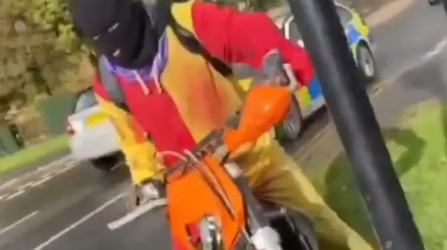 Man in clown costume on bike