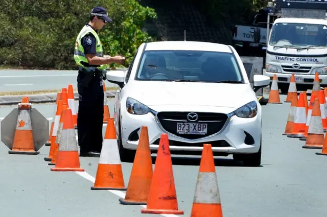 A motorist passes through a border control checkpoint on the Queensland-New South Wales border at Coolangatta, Australia