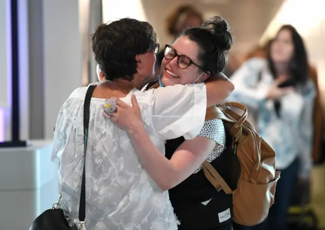 A passenger is greeted after arriving on the first flight from Melbourne to Brisbane since border restrictions were lifted