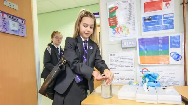 A schoolgirl sanitising her hands