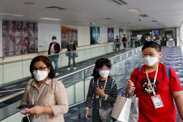 Passengers wear face masks as they board a flight at Hong Kong airport