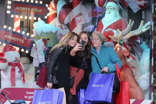 Three women in Ireland take a selfie in front of a Christmas display